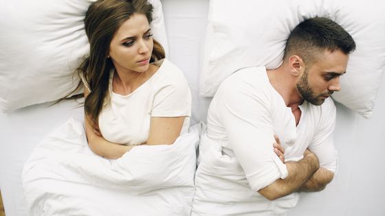 Couple traversant une période de tension, chacun tourné de son côté du lit
